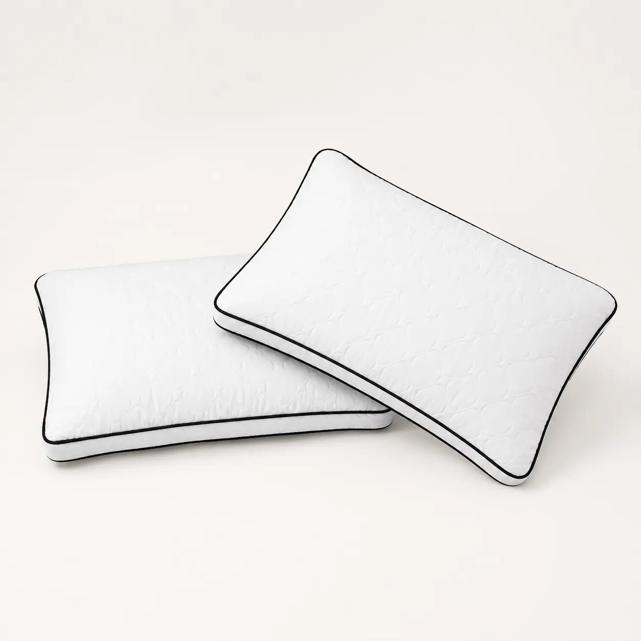 Two white quilted pillows with black piping in a studio